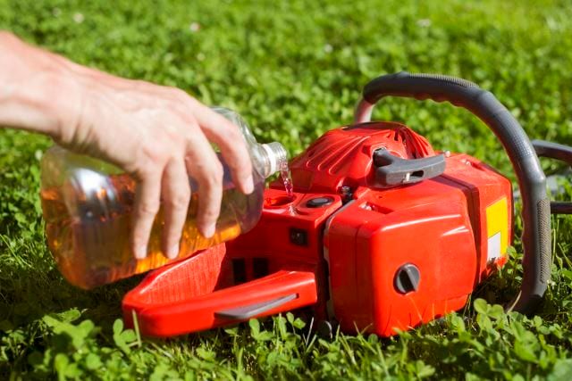 Handyman replenishes the oil in chainsaw for chain maintenance