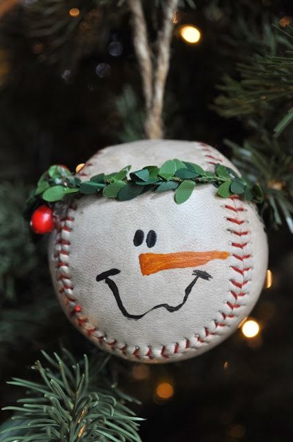 Baseball ball decorated with leaves and drawn eyes, nose and smile to show a snowman face