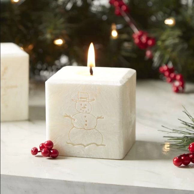 White lit candle with carved snowman in its body
