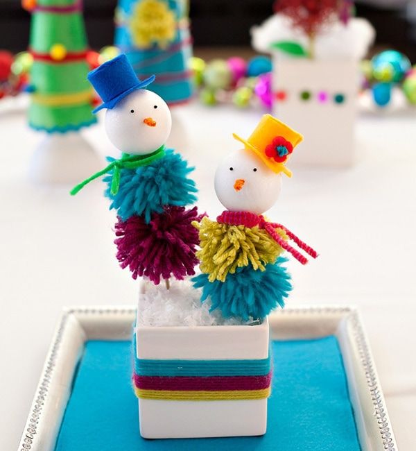Two mini-snowman with pompom bodies with blue and orange hat on each