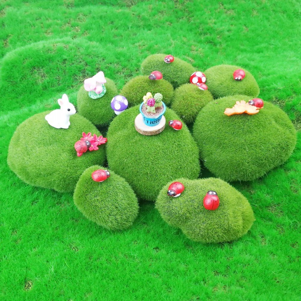 Assorted artificial moss rocks on a greenry ground with decorative red bugs,rabbit and flowers.