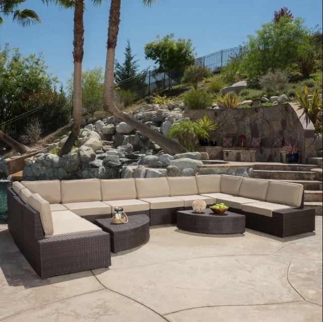 Rattan sectional set with cushions placed on a stoned walkway with bedrock on the background