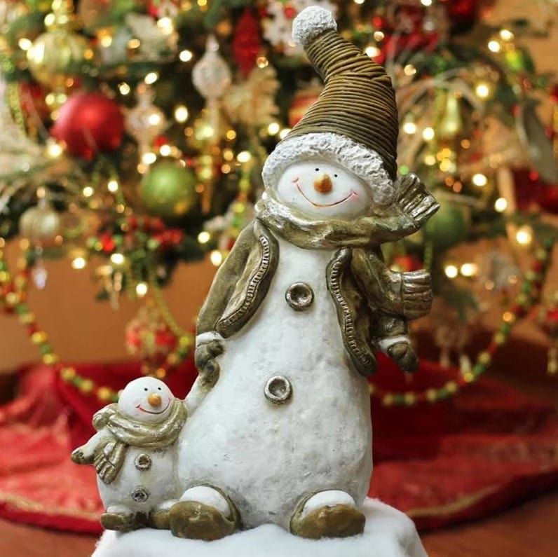 Cute smiling snowman holding miniature one with a blurred Christmas tree on the background