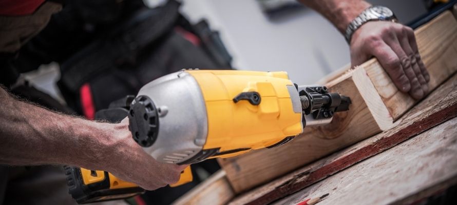 Caucasian Construction Worker Creating Wood Elements Using Powerful Nail Gun Tool
