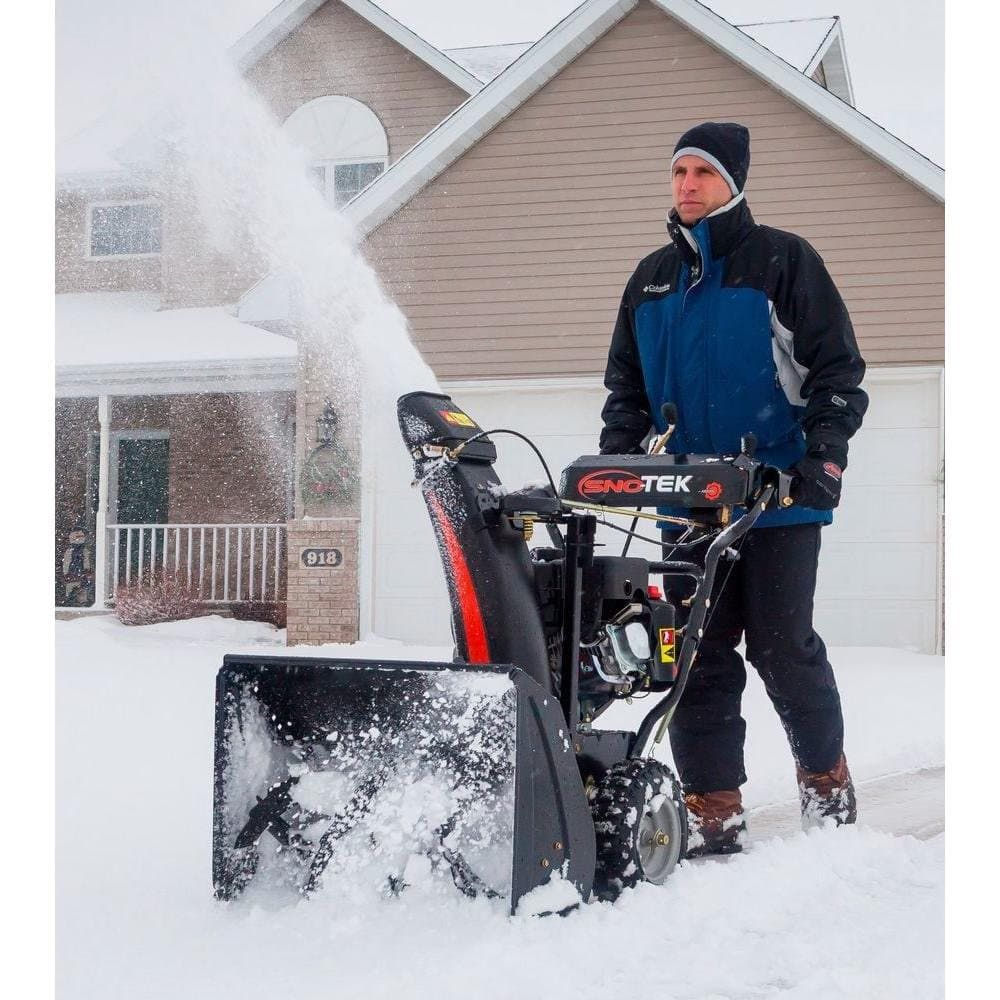 Man holding his Sno Tek Snow Blower driving it to clear snow on his yard.