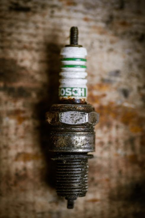 Used spark plug on a wooden background.