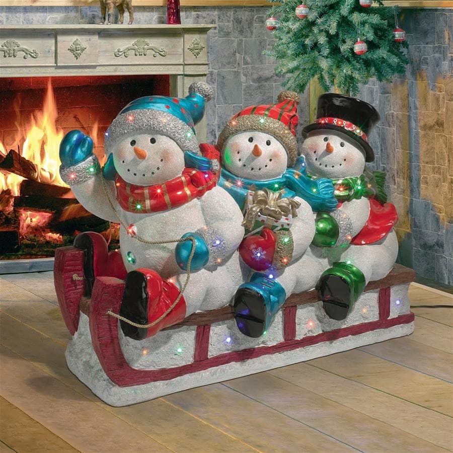 Three snowman riding on a sleigh indoor with fireplace on the background