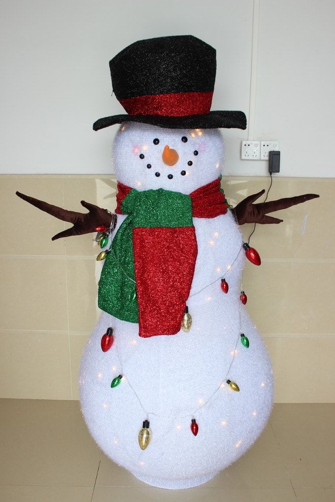 Indoor DIY snowman adorned with hat, scarf and draped in colorful lights around its body
