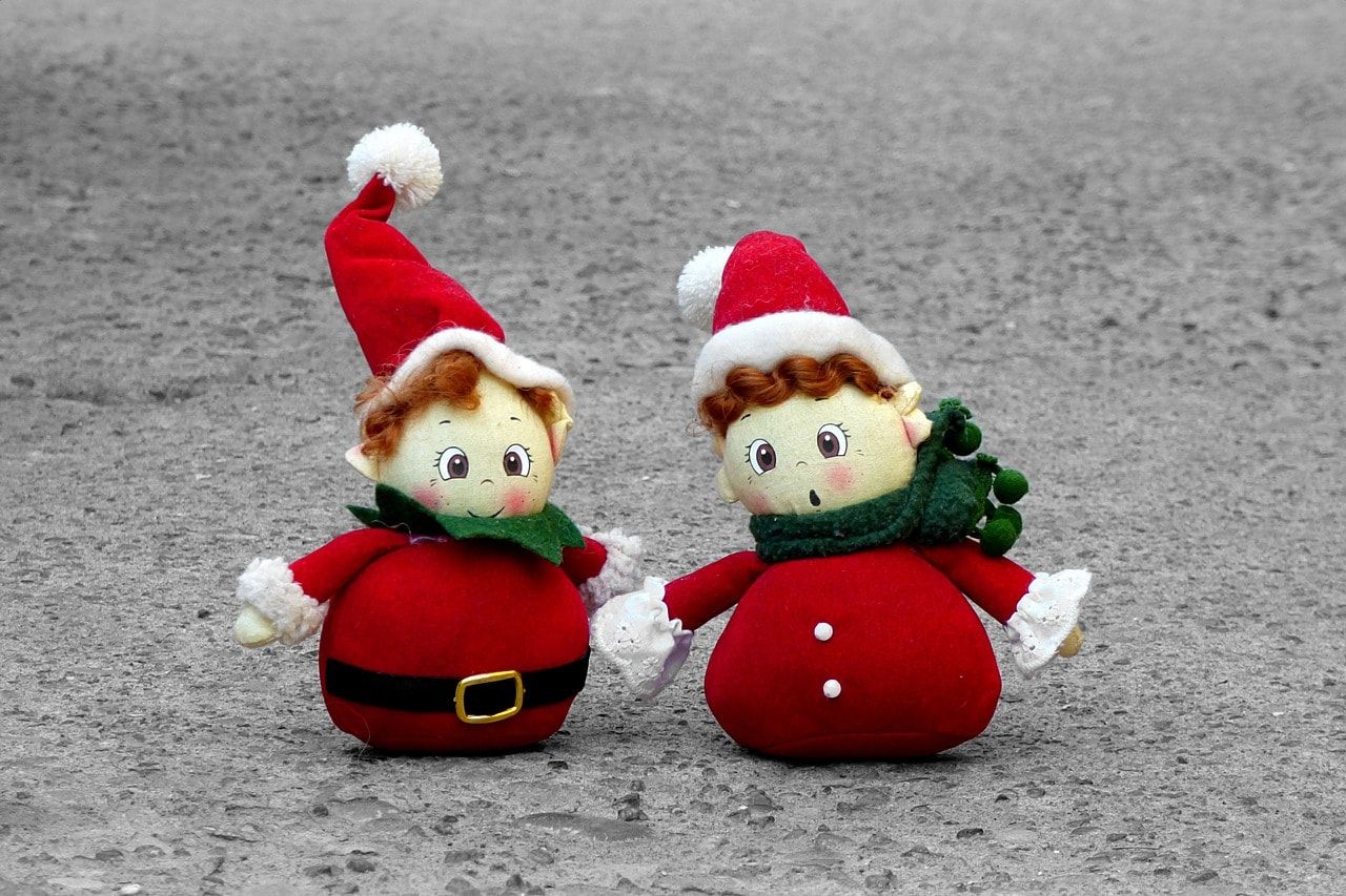 Two cute little santa dressed snowman standing on a solid pavement