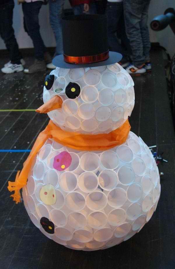 Plastic white cups recycled and joined together to form a body of a snowman adorned with recycled material as scarf