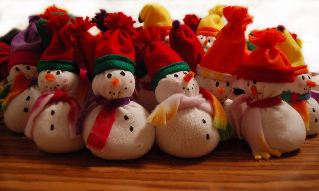 Several numbers of cute snowman made out of socks adorned with scarfs and hats