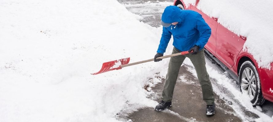 Man Removing Snow From His Driveway With a Shovel