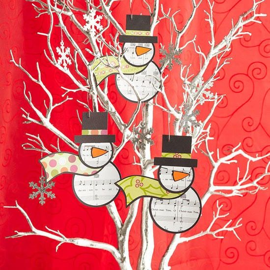 Snowman with musical symbols printed in its body and head hanging on the twigs of the indoor tree