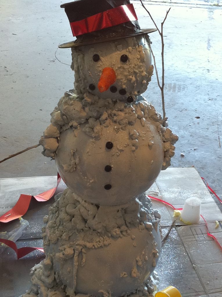 Messed up Three balls of cement adorned with black buttons to look like a snowman wearing a hat