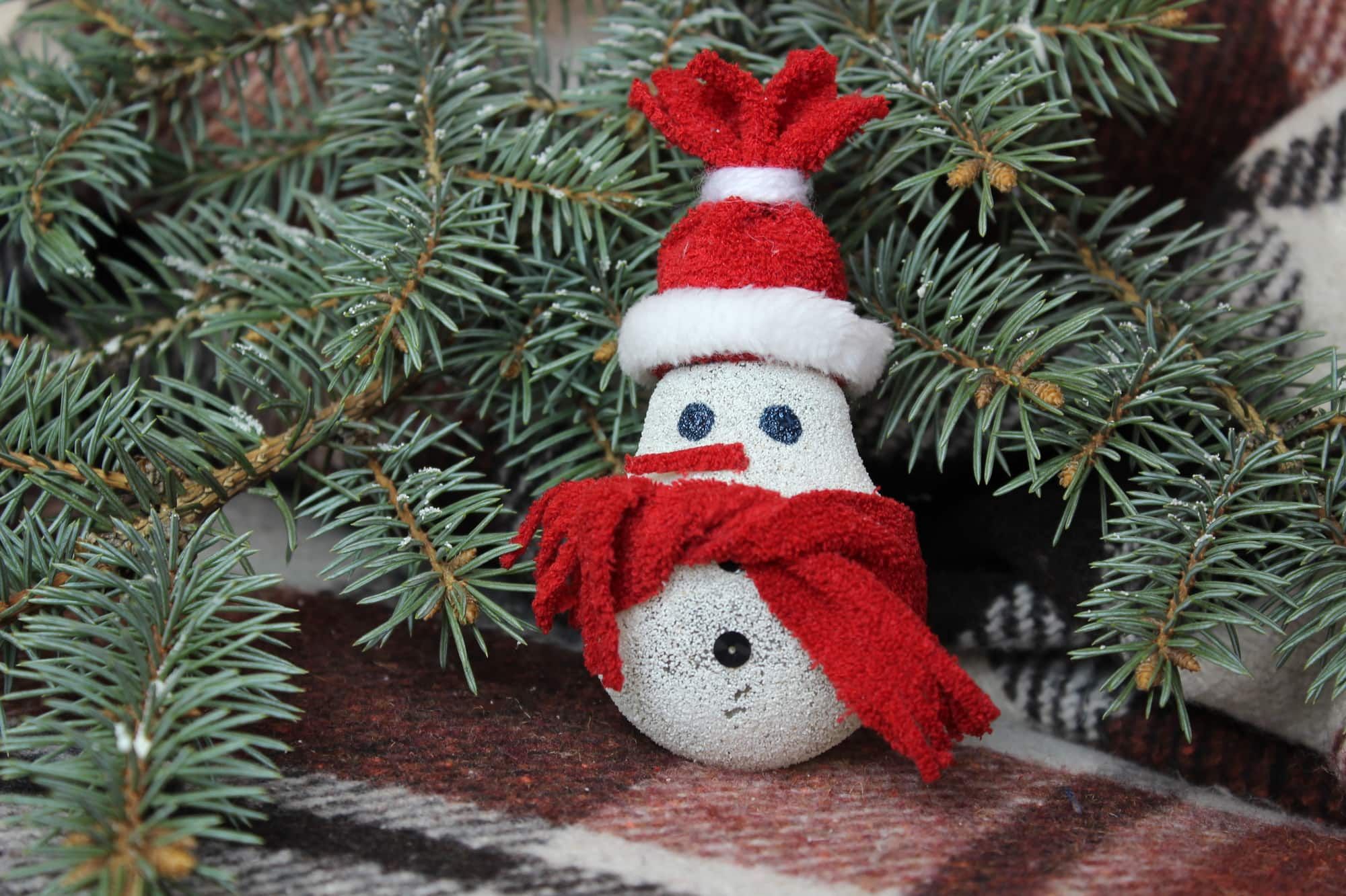 Snowman made from light bulb near Christmas tree