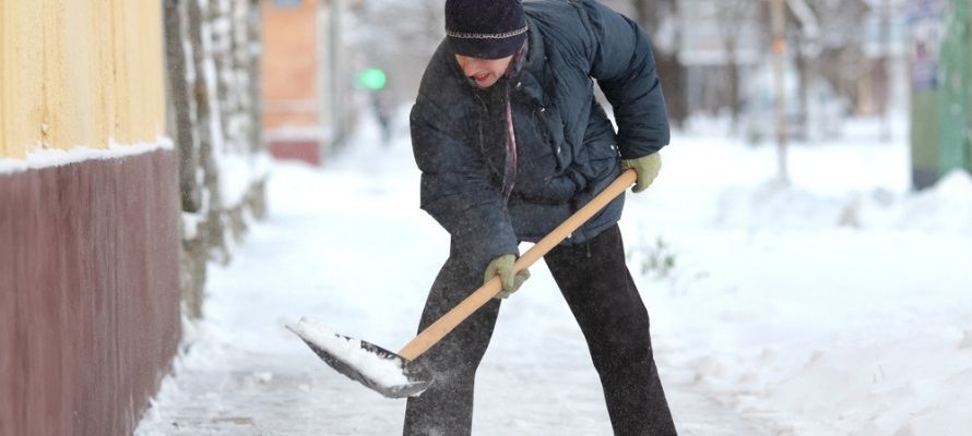 Caucasian woman cleaning snow from sidewalk with shovel