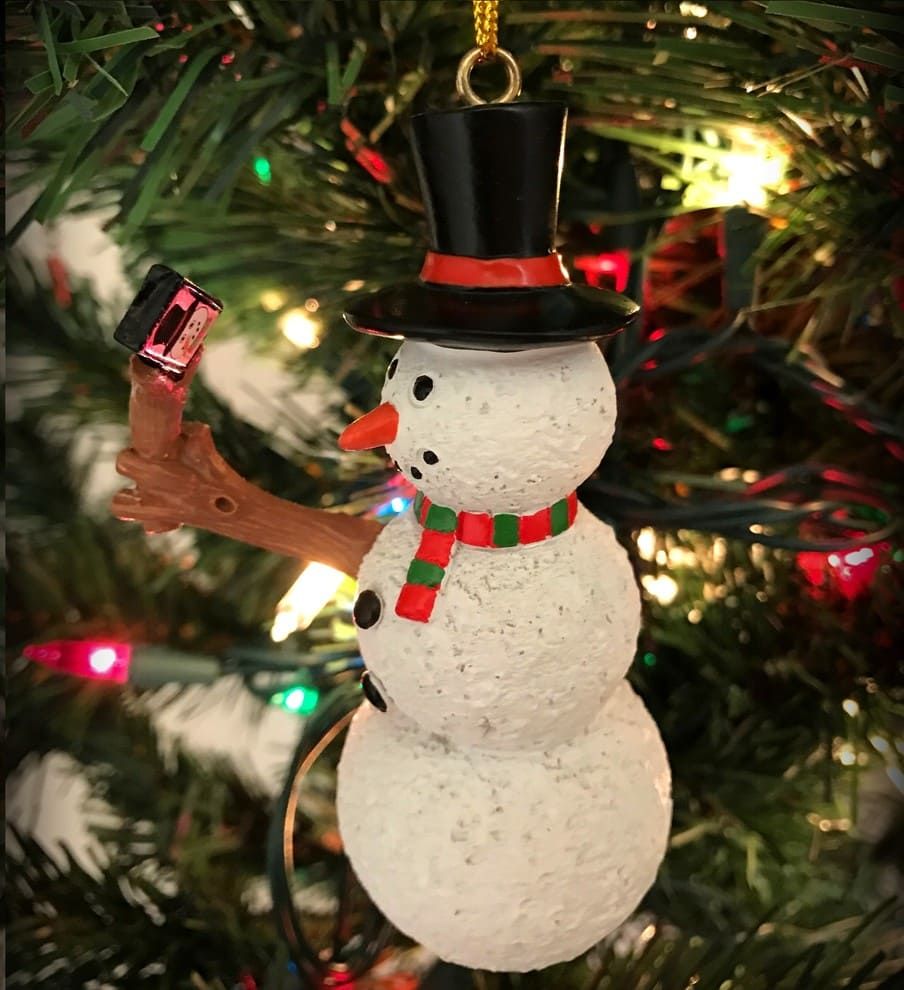 Christmas tree snowman decoration with a handmade wooden arm holding a miniature camera taking a selfie