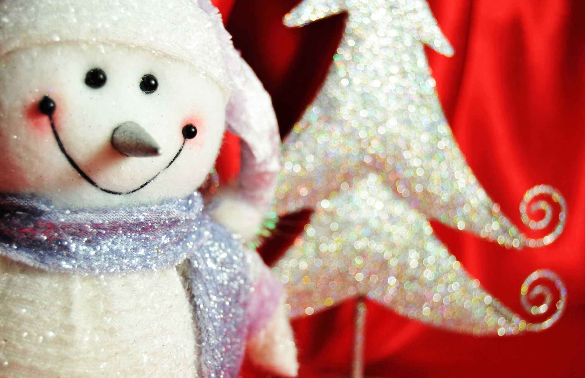 Close up snowman shining in glitters with blurred tree like material on the background