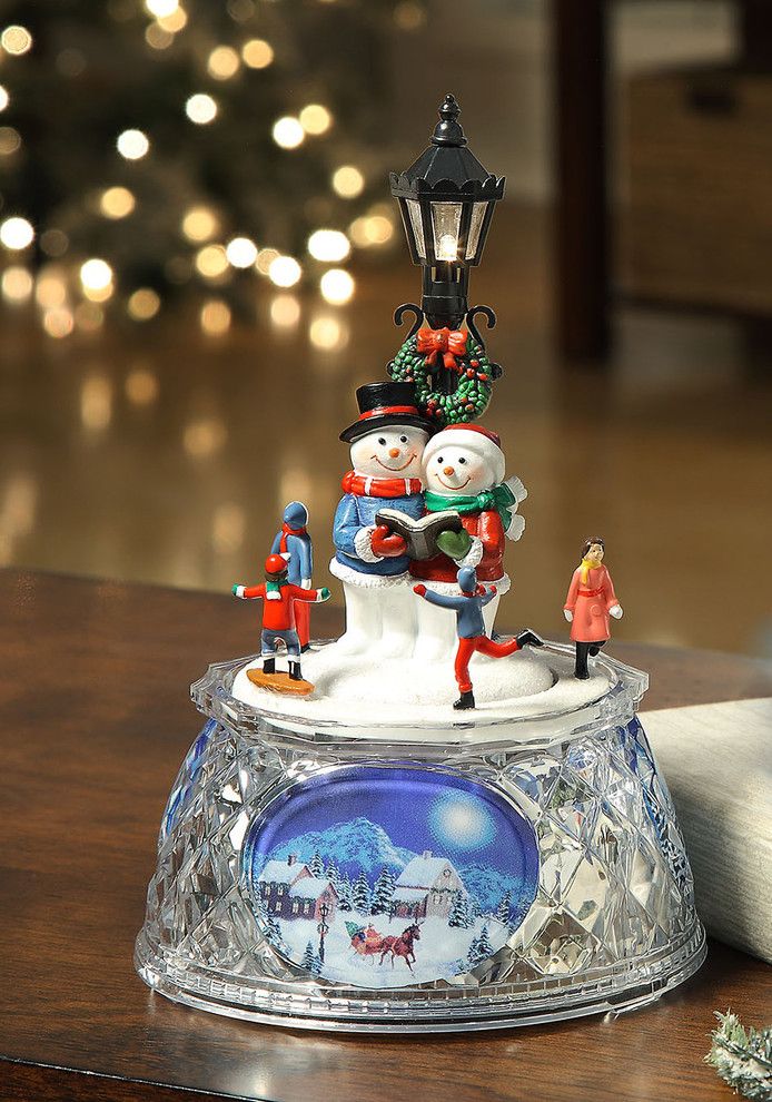Miniature snowman couple holding a book under a street light surrounded by four little human all placed in a rounded crystal like glass