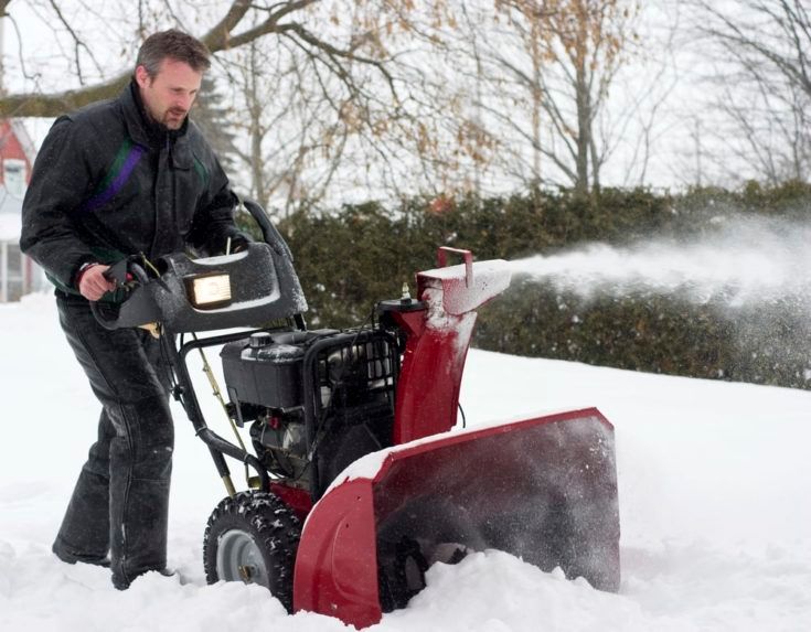 man using snow blower during winter storm