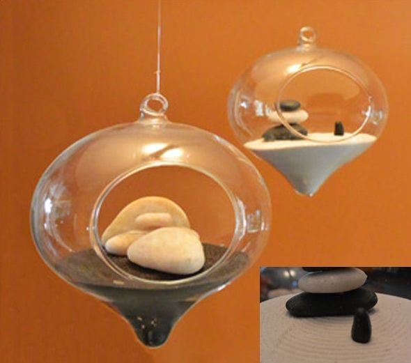 Hanging Round glass with sand inside and several white and black stones.