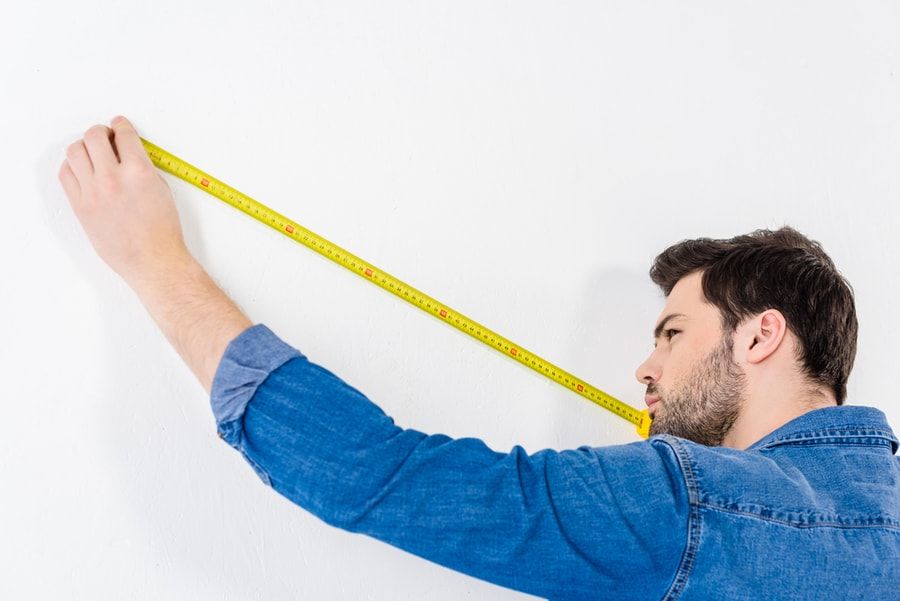 Man holding a measuring tape in a white background