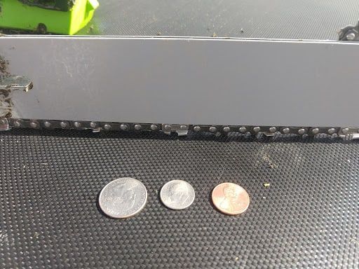 Three different coins laid down on a flat surface with a chainsaw on the background
