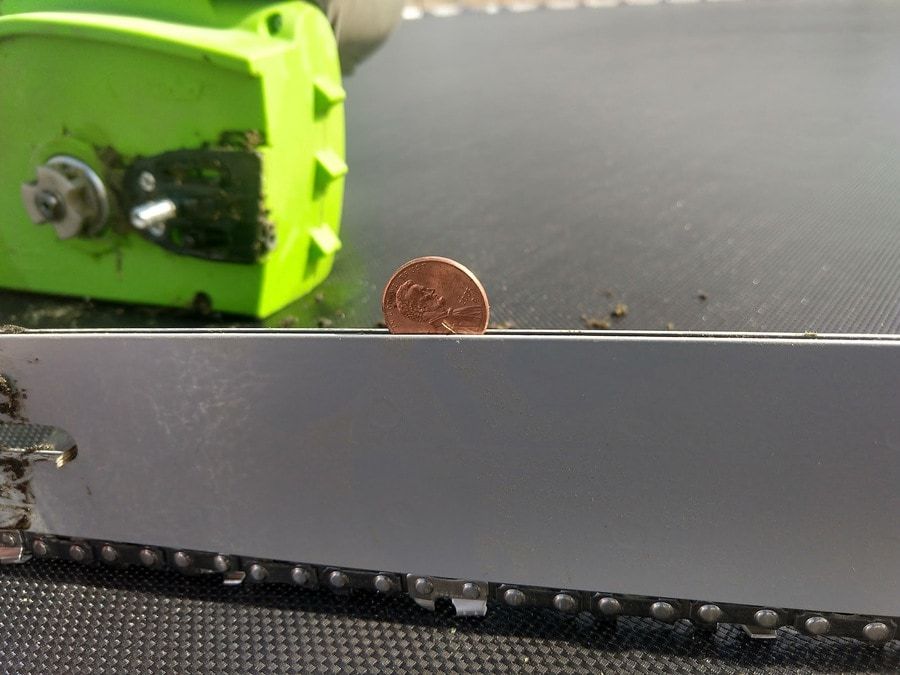 A coin placed in between chainsaw metal plates with chainsaw chains removed