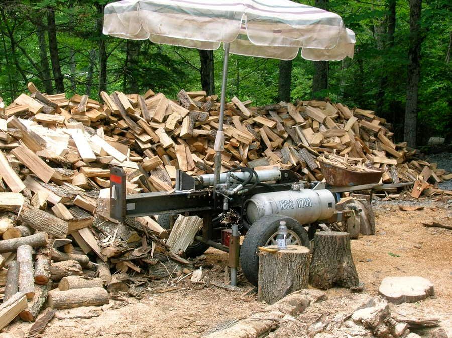 a custom small log splitter with cut logs around it on the backyard