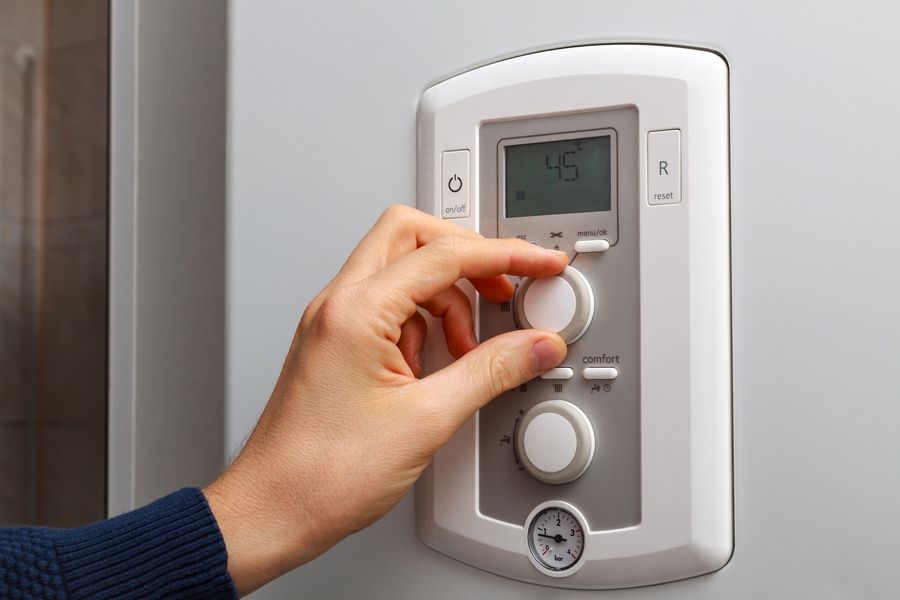 Men hand regulate temperature on 45 degree in control panel of central heating