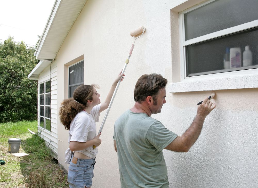 A father and daughter painting their house together.