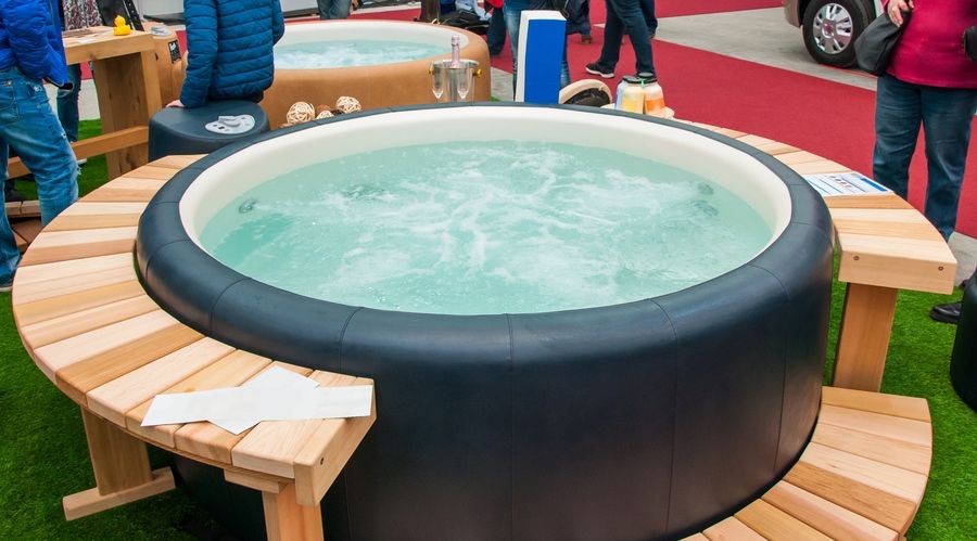 Detail view of luxury beautiful hot tub for relaxing, with decoration, towels, bottle of wine in nice interior.