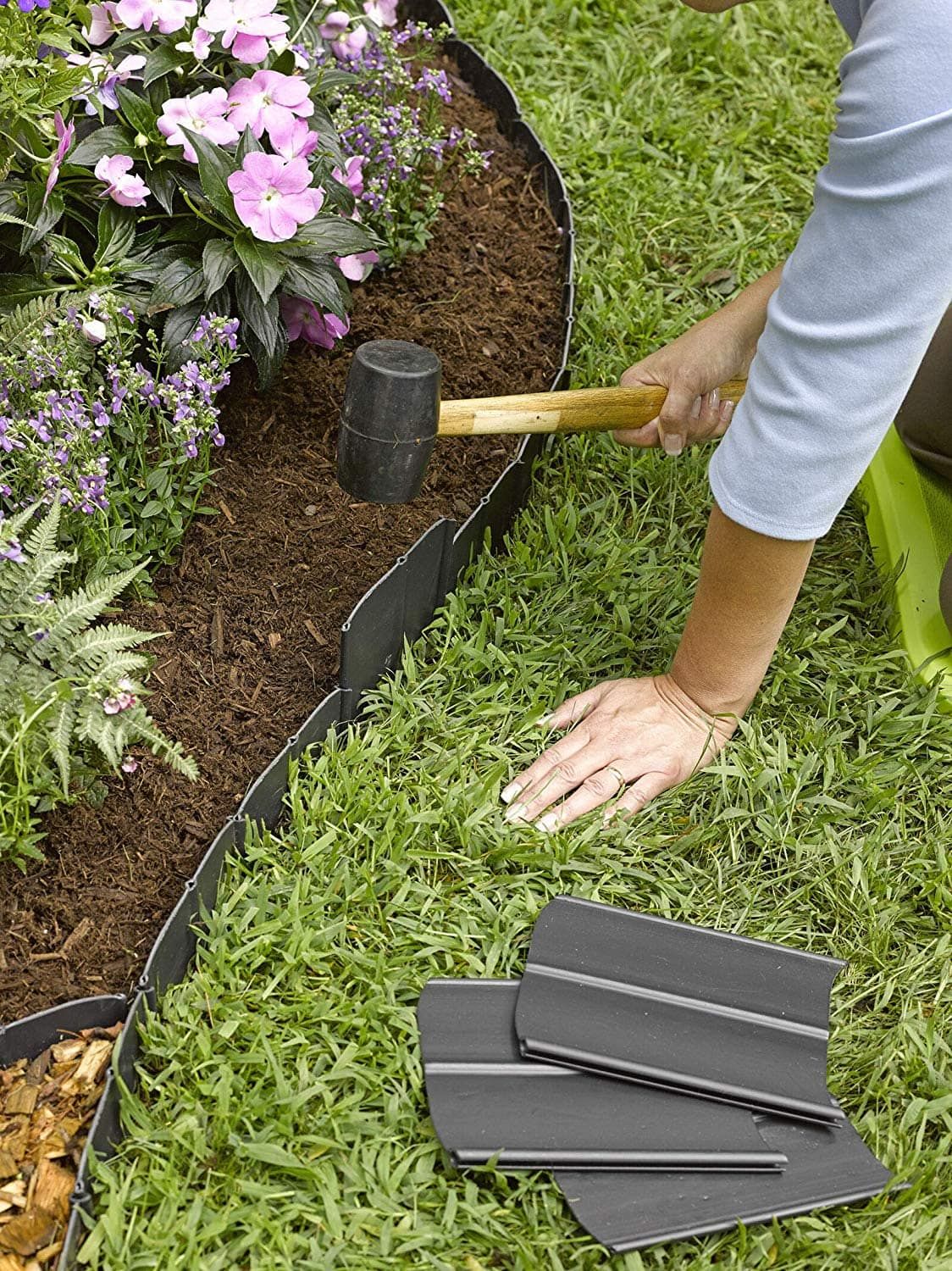 Close up woman hands holding a pallet to install metal lawn border edging.