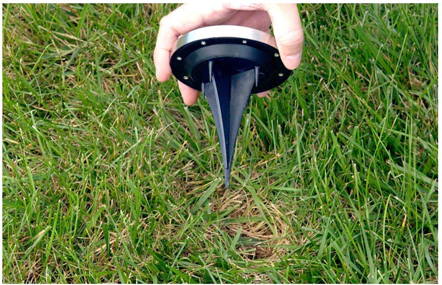 upclose of hand holding a disk light ready to be install on lawn.