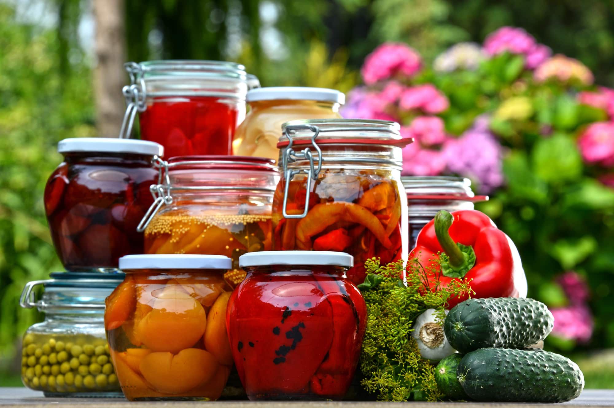 Jars of pickled vegetables and fruits in the garden. Marinated food.