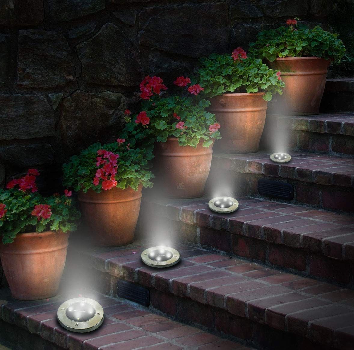 Solar disk lights perfectly arrange on the steps beside flower pots.