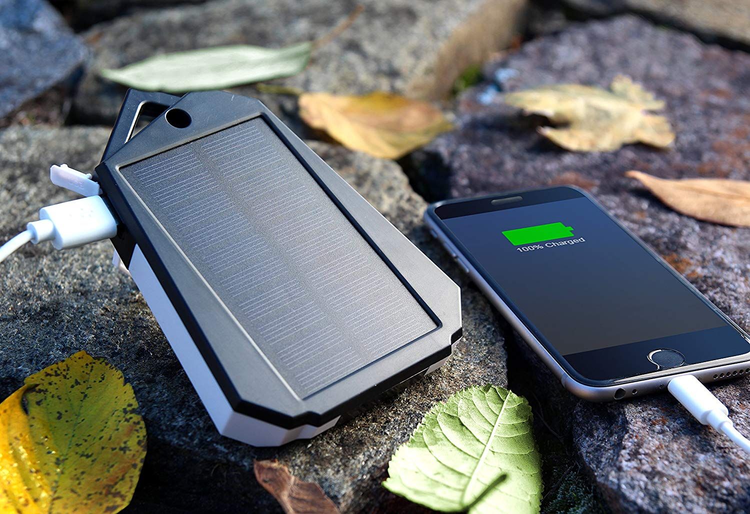 Touch of ECO Sunvolt Dual USB Solar Powered Charger charging a smart phone place on top of a flat surface rocks.