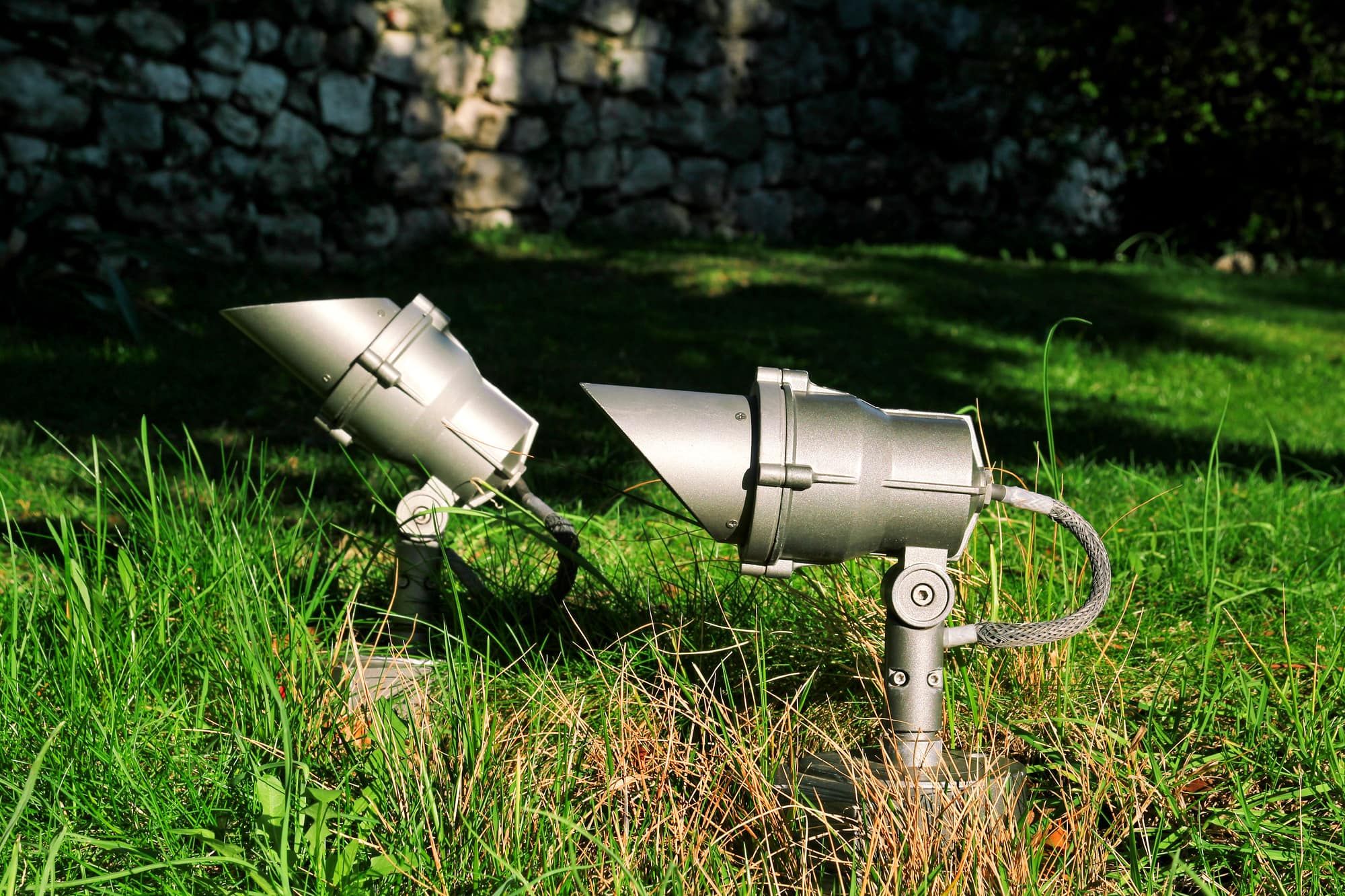 Close up of spotlights in the green field. Energy saving outdoor floodlights, small reflectors on green grass. Light bodies. A ground spotlight in green yard. Lamp LED in the park, garden background.