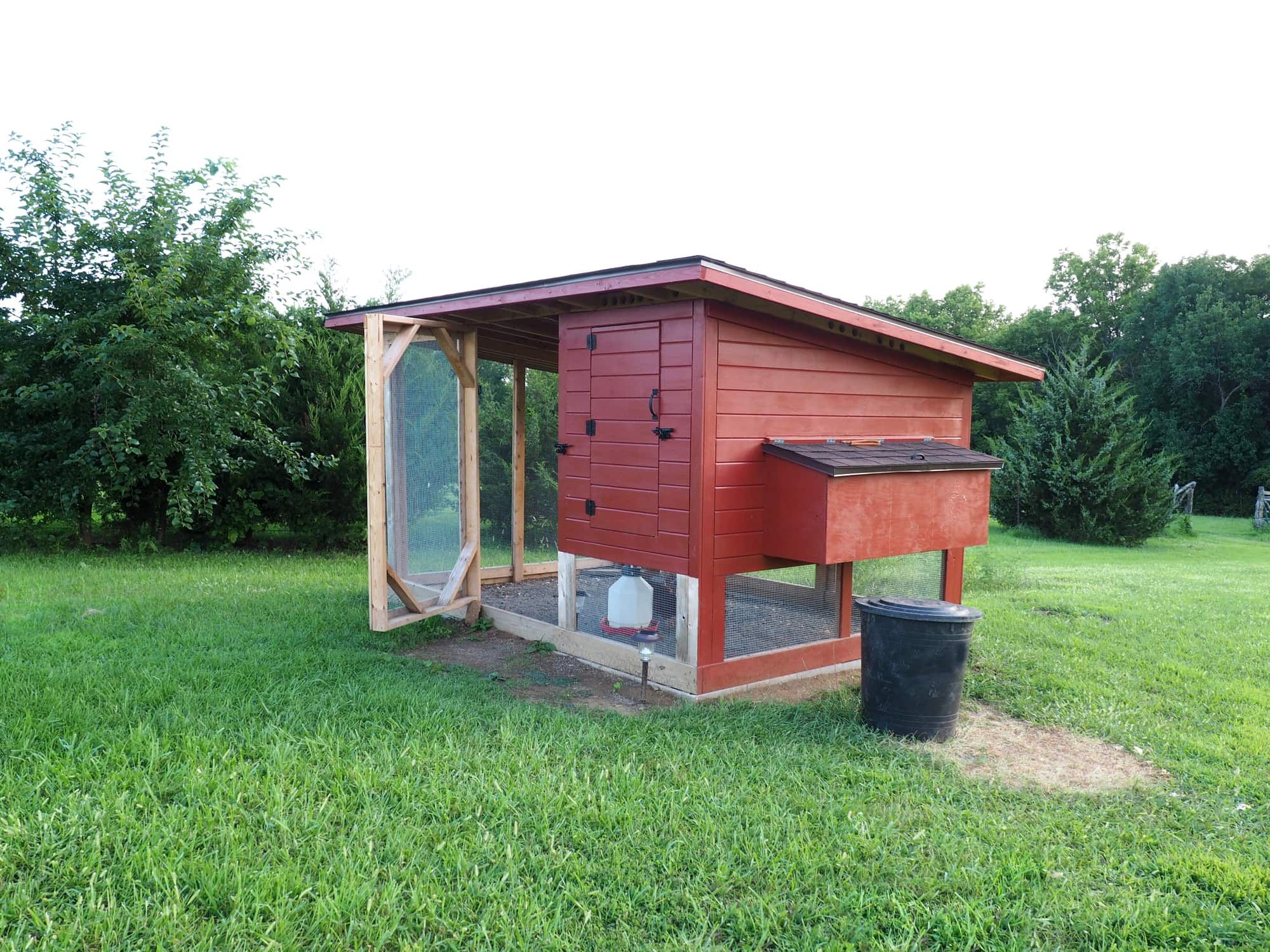 red chicken coop made of wood and metal screen