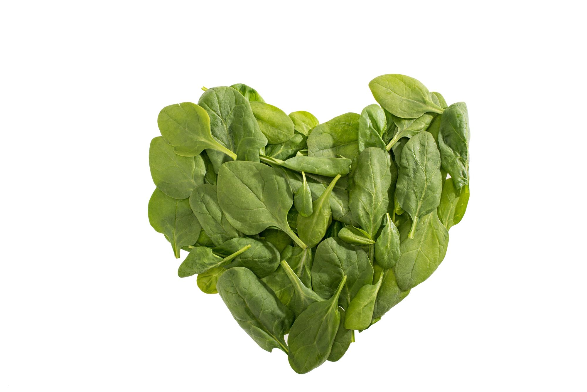 Top view of heart shaped green spinach leaves isolated on white, food styling