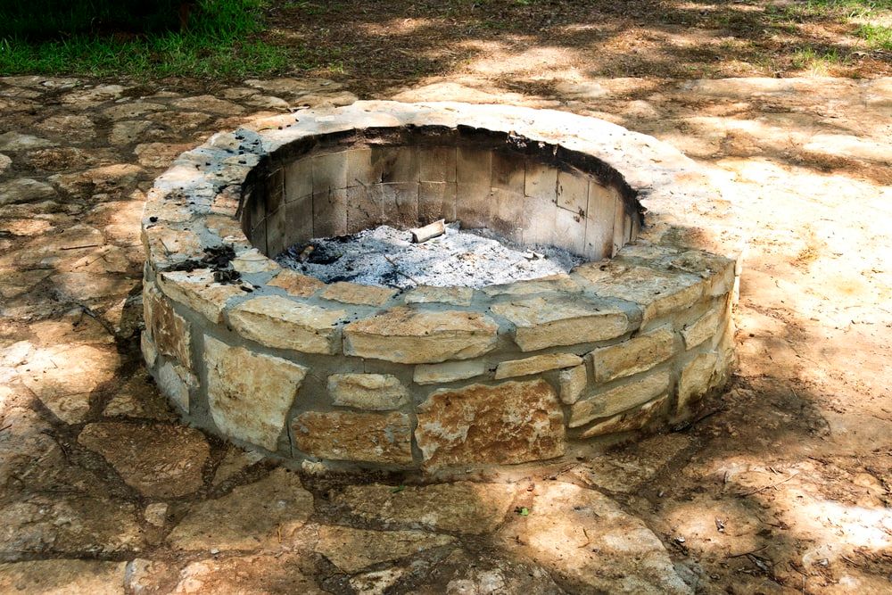 An empty stone fire pit with just ashes left
