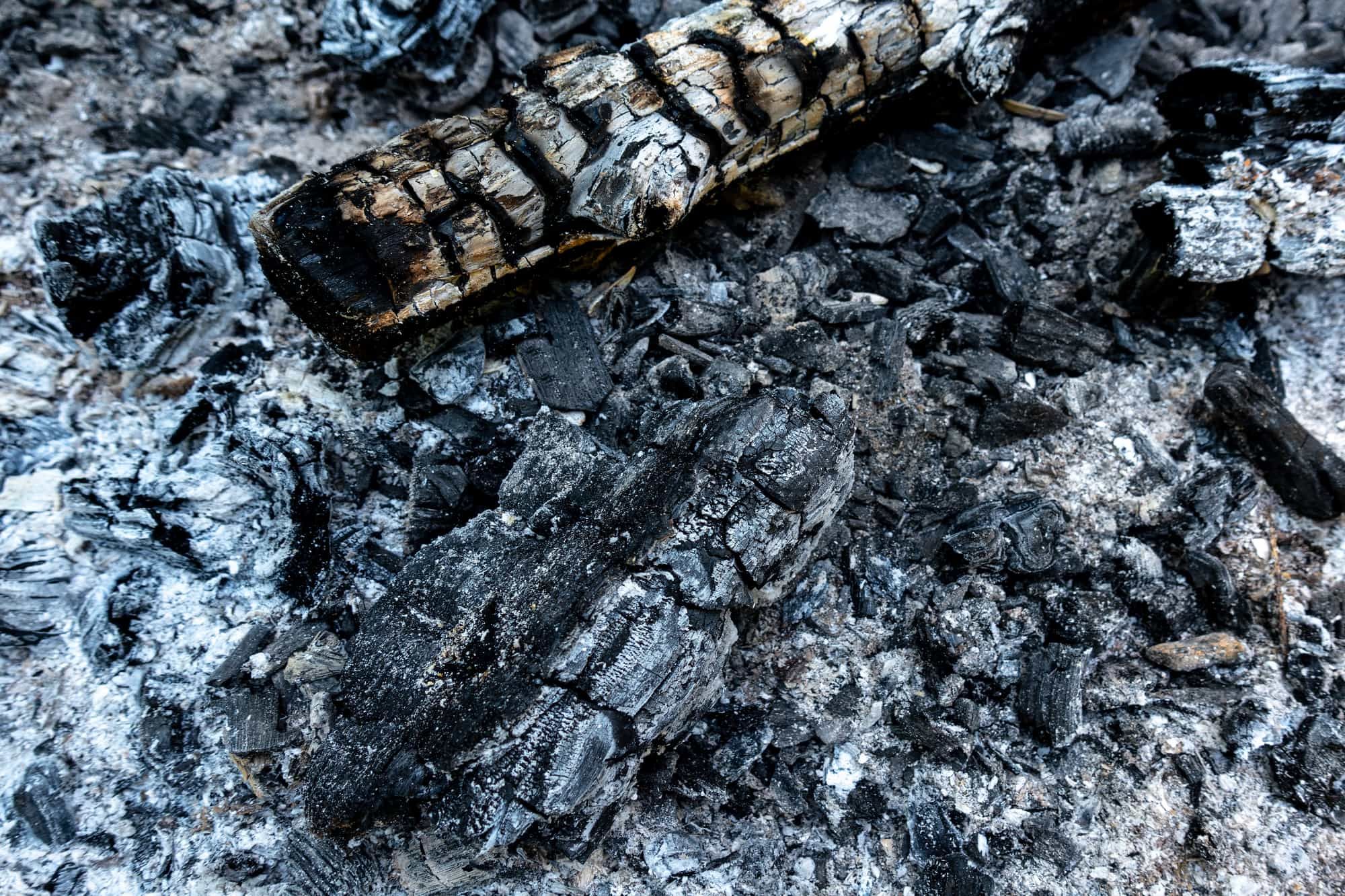 Charred wood and ash in an extinguished fireplace in closeup