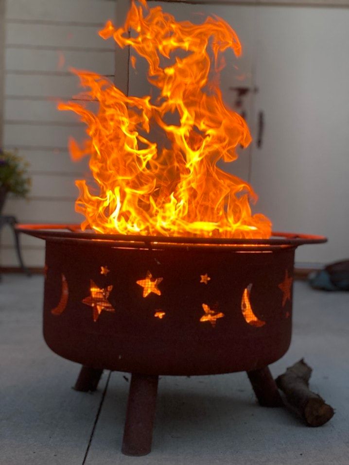 firebowl with moon and star cutouts lit on patio