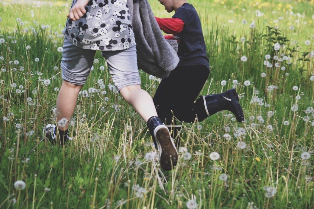 kids running in a field playing tag