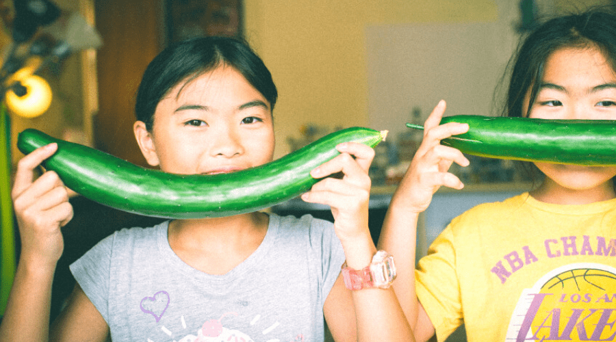 two girls holding homegrown cucumbers