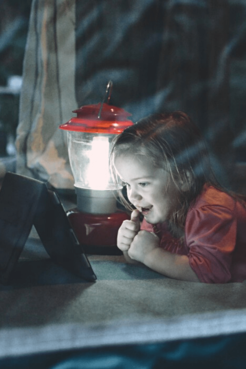 lantern light flashlight in tent with small child using tablet