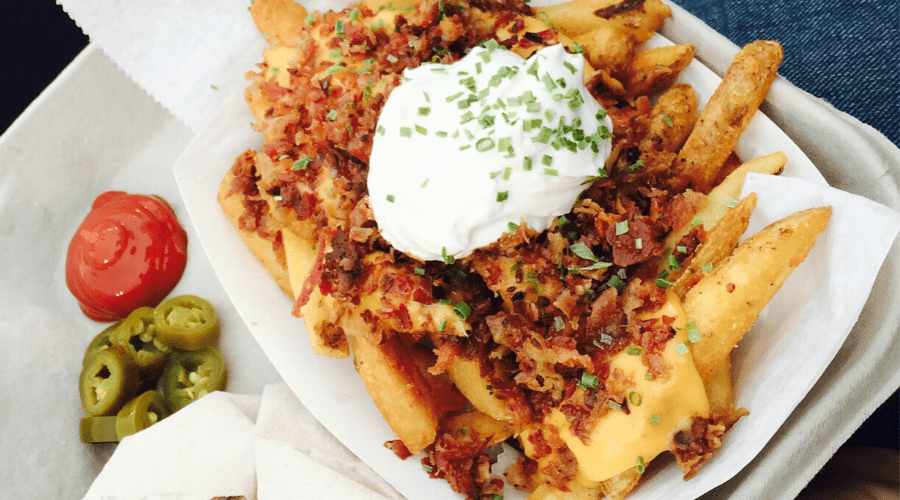 loaded fries with sour cream, bacon chives, cheese in a disposable box