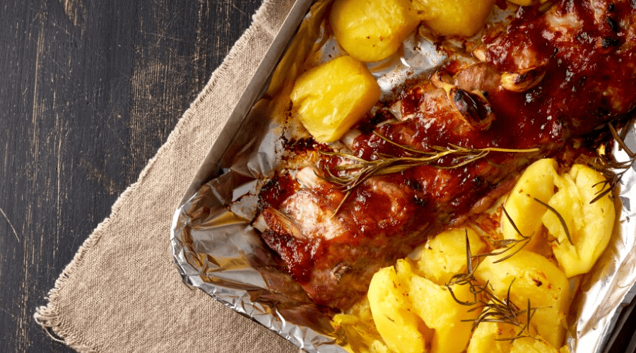 bbq and potatoes in foil pan on table