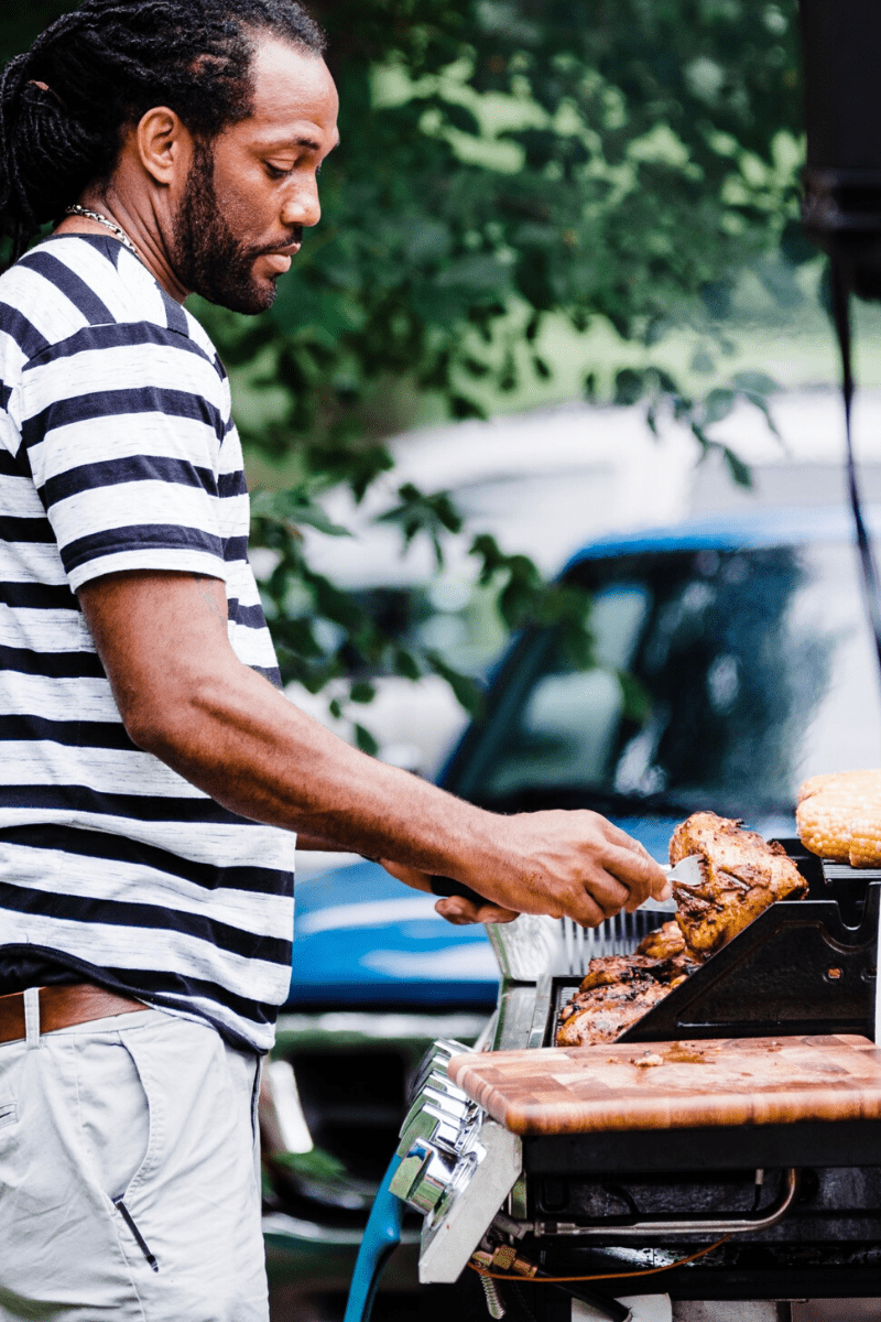 man cooking on propane gas grill outdoors