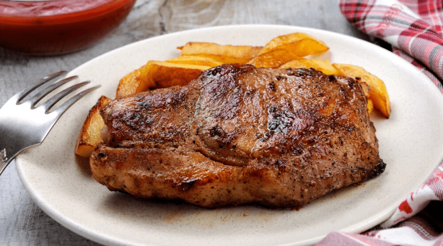 Sweet &amp; Spicy Pork Chops recipe on plate with fries and tablecloth
